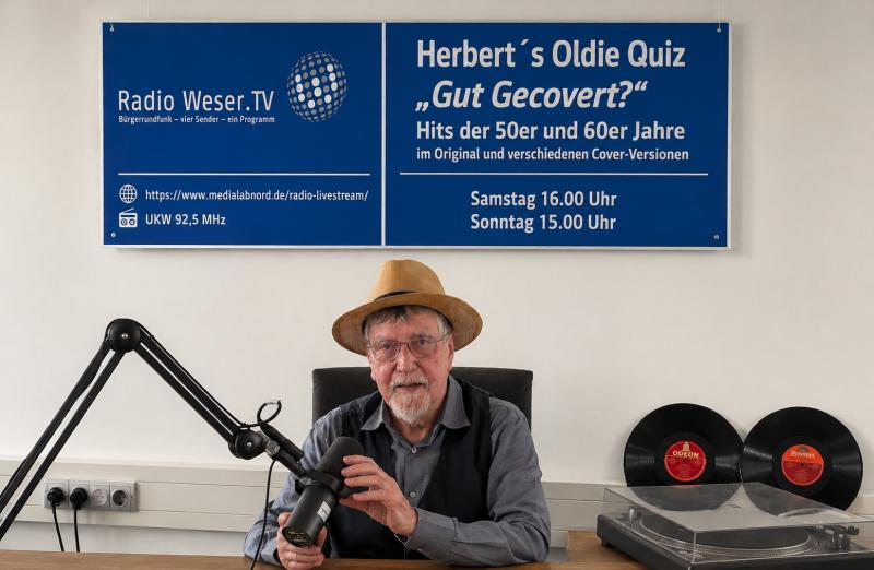 Herbert mit Strohhut im Studio vor einem Plakat mit der Aufschrift Herberts Oldie Quiz und den Sendeterminen